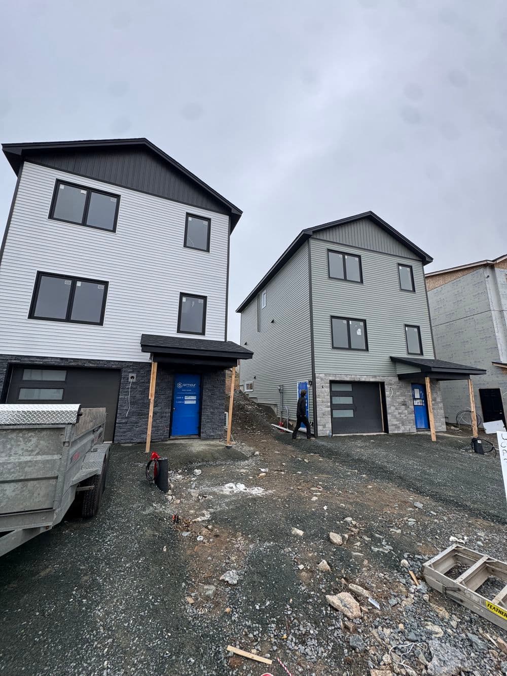 Two modern homes under construction with gray exteriors and unfinished landscaping.