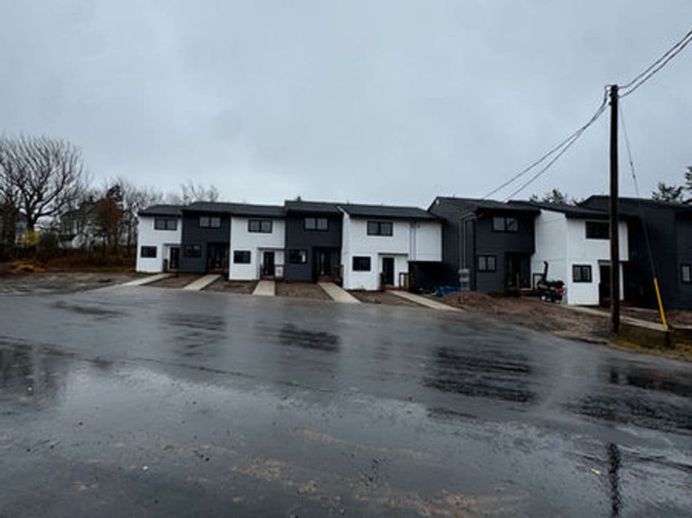Modern townhouses in a rainy landscape with empty parking spaces.